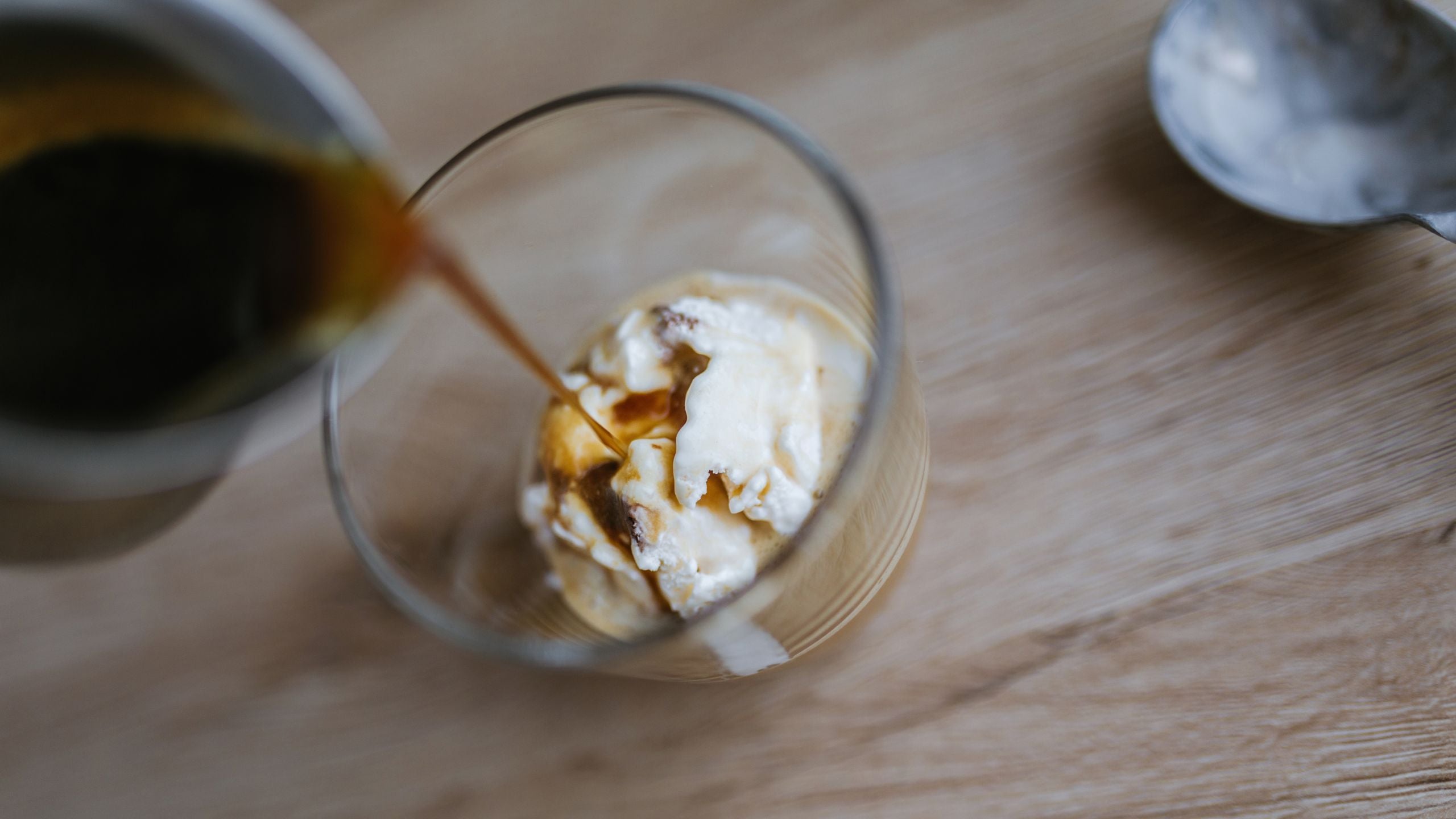 Espresso slowly being poured onto vanilla ice cream making an affogato..