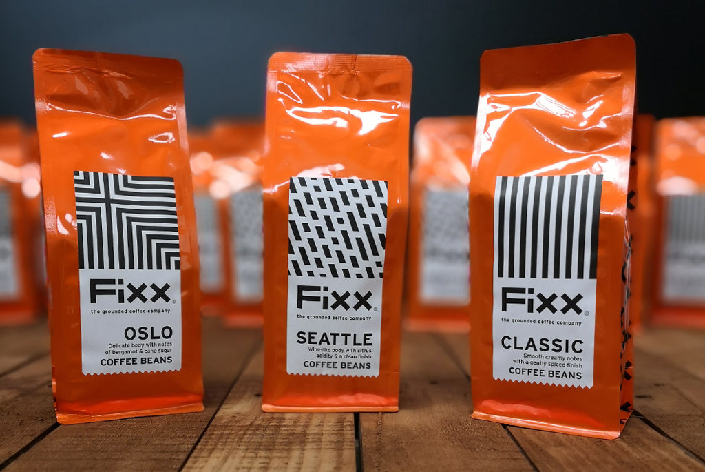 A selection of orange FiXX Coffee bags on a wooden tabletop