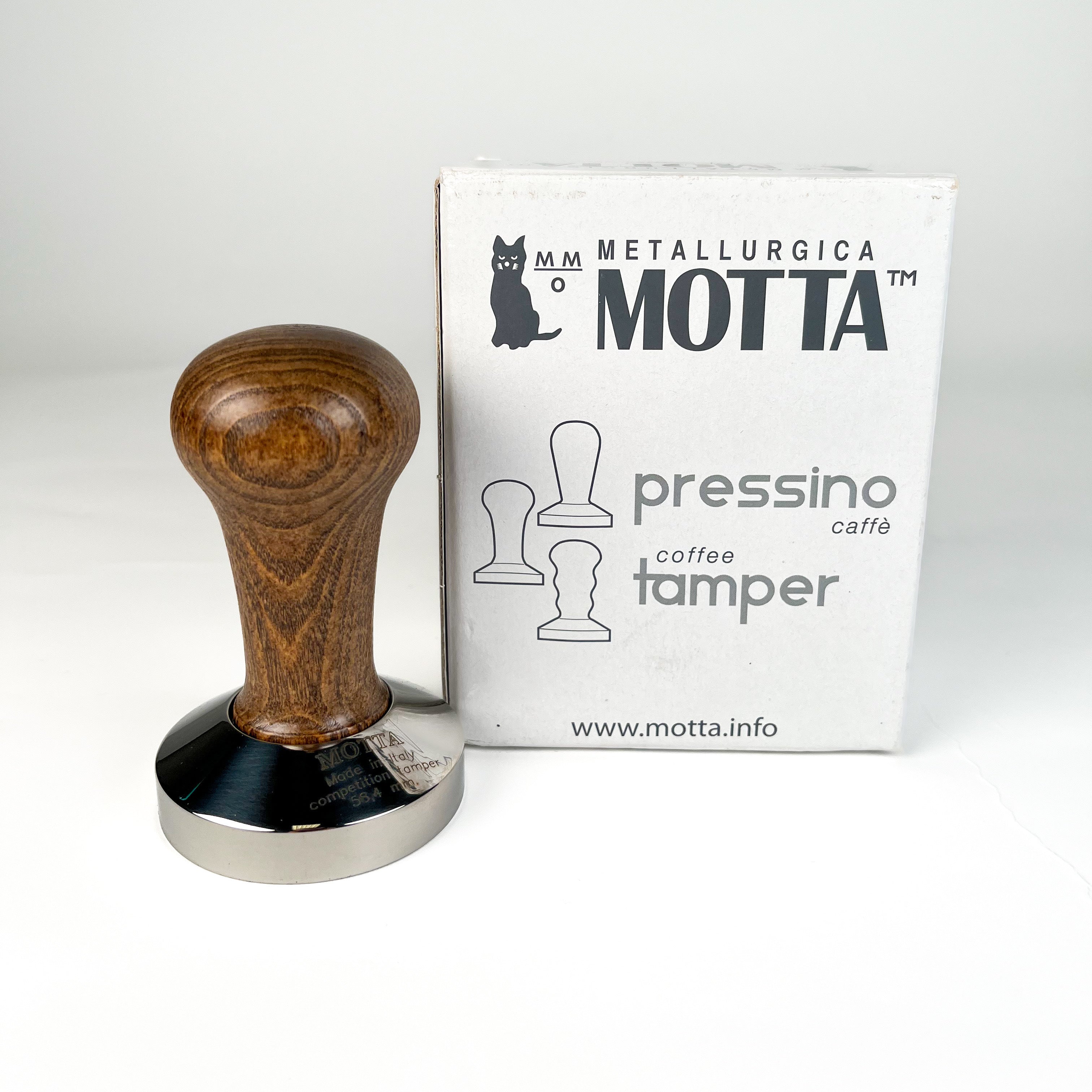 A stainless steel Motta coffee tamper with a wooden handle, featuring a 58.4mm base diameter beside its original packaging.
