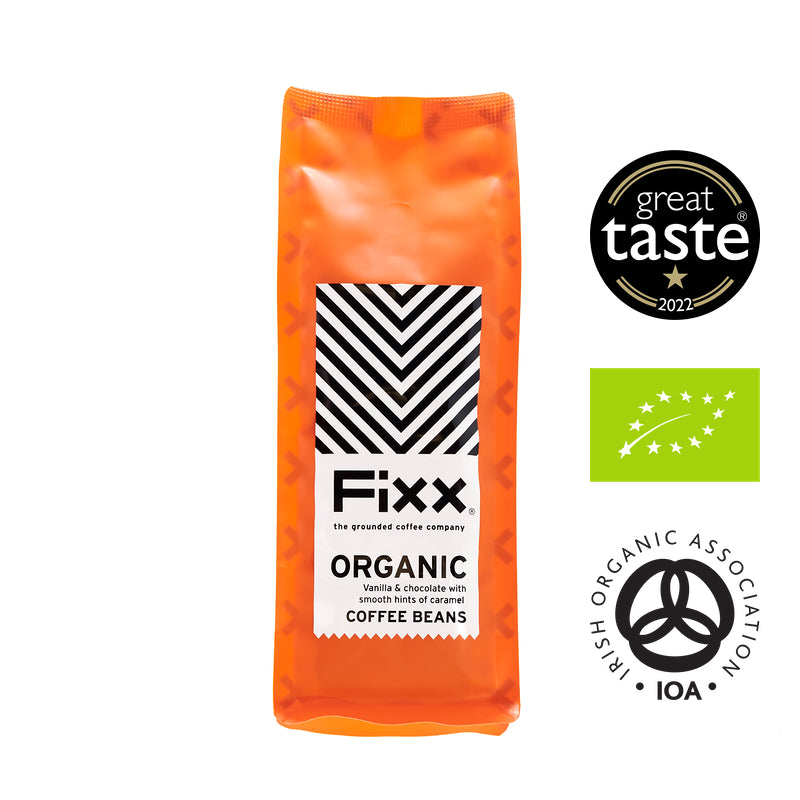 A bag of FiXX Organic coffee beans with a label indicating it is an organic product with a black and white pattern. There are badges for a Great Taste award and an Organic Association, indicating the quality and certification of the coffee.