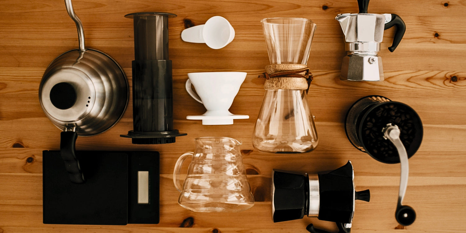  A collection of different coffee brewers and equipment arranged in a design on a wooden table.