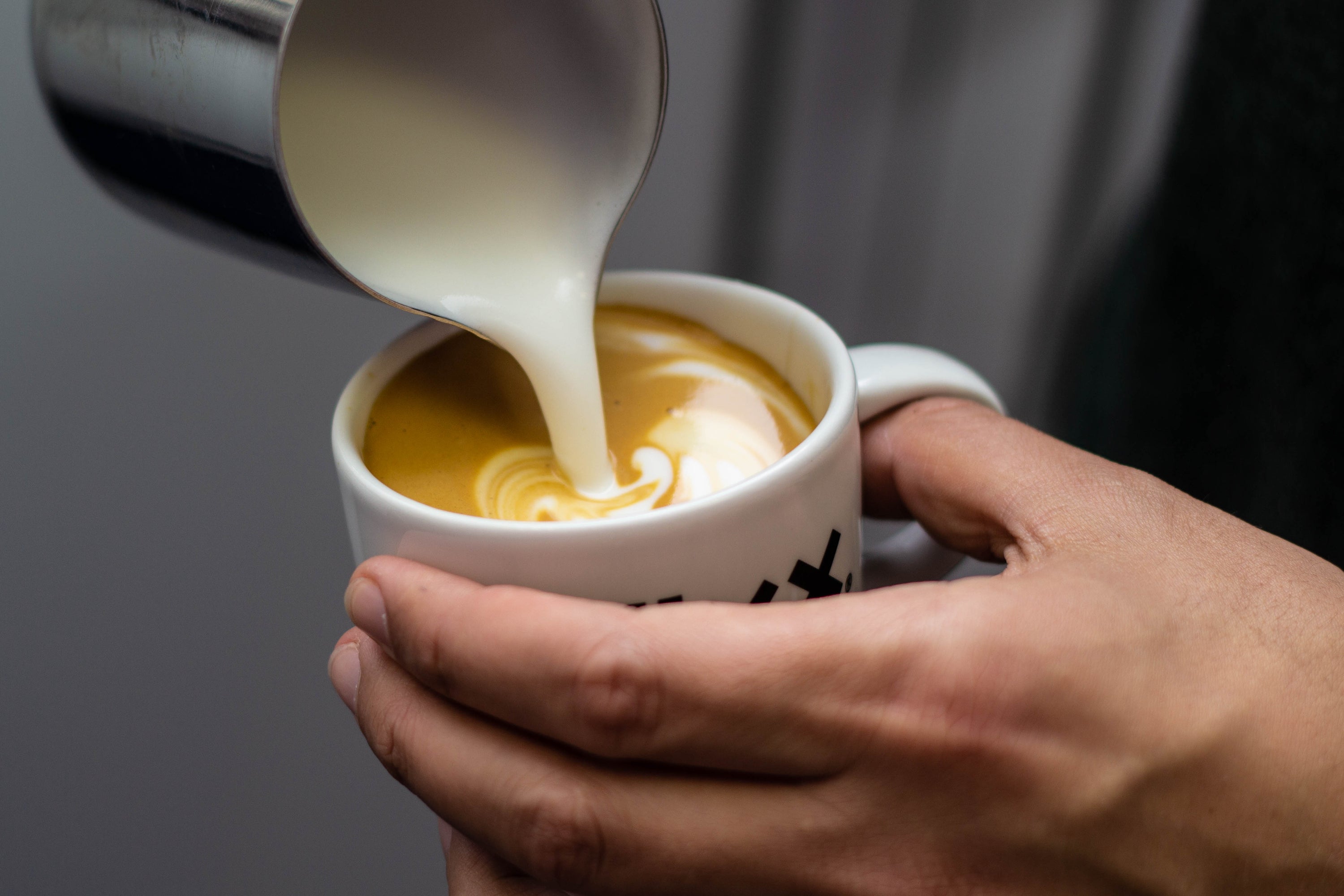 Oat Milk being pour into a cup of FiXX coffee to make a latte