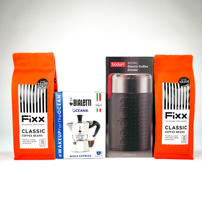 A product bundle featuring two orange bags of Fixx Classic Coffee Beans, a white and blue box of Bialetti Oceana Moka Express, and a black Bodum 31500 electric coffee grinder, arranged against a light gray background.