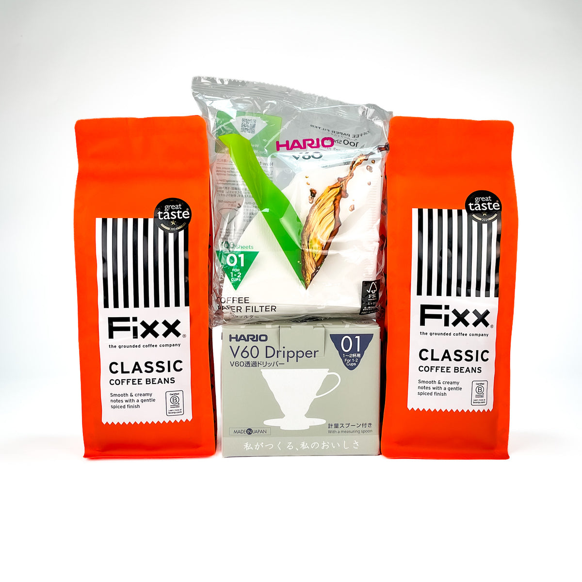 Three coffee-related products arranged against a plain white background: two orange Fixx coffee bean bags flanking a central Hario V60 dripper box and a Hario coffee filter pack.
