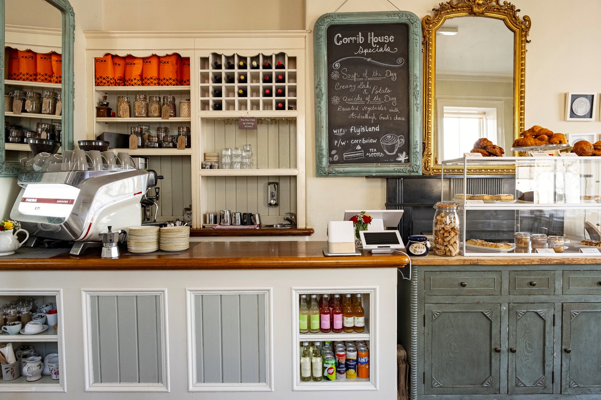 A cafe counter top with an espresso machine beside bags of coffee and pastries.