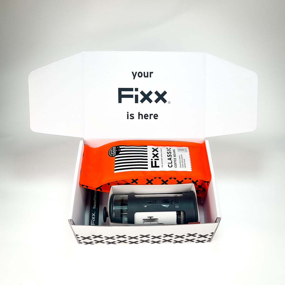 An open white FXX-branded box containing a bright orange wrapped item labeled &