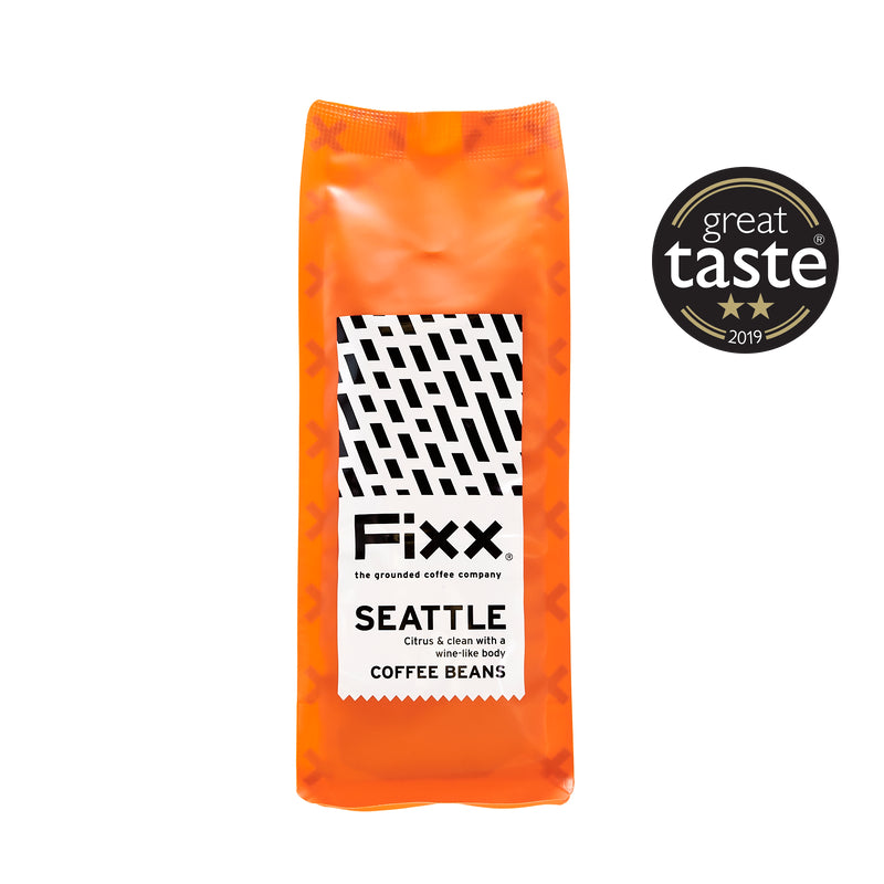 An orange package of FiXX Seattle coffee beans with a white background, black text, and a &